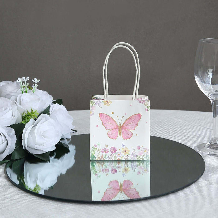 Pink butterfly gift bag on a mirror with white roses and a glass.