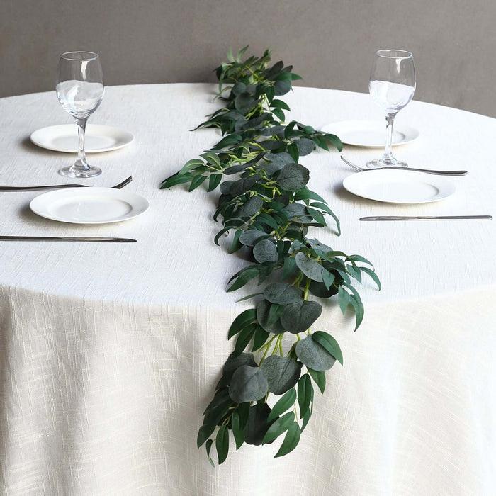 Elegant green foliage runner on a dining table with glassware and plates.