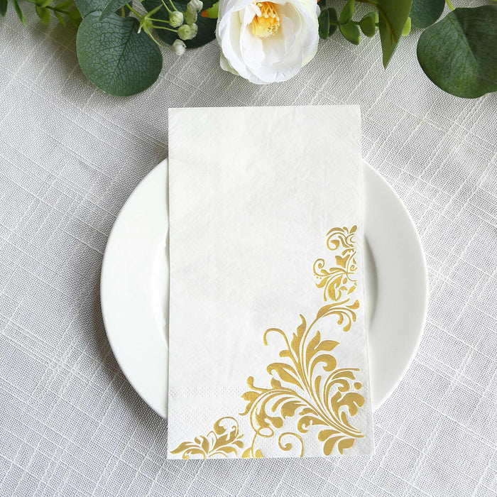 Elegant white napkin with gold floral design on a plate.