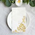 Elegant white napkin with gold floral design on a plate.