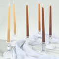 Elegant tapered candles in crystal holders, arranged on soft fabric.