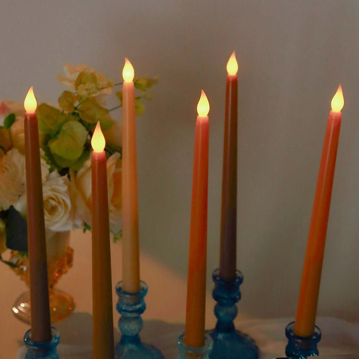 Colorful taper candles in blue holders with a floral arrangement in the background.