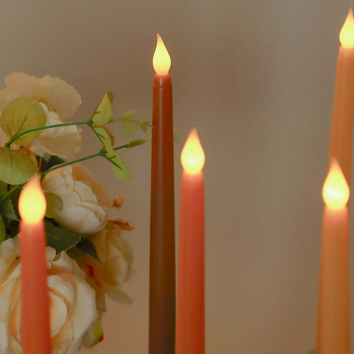 Colorful LED candles with a floral arrangement in a soft-focus background.
