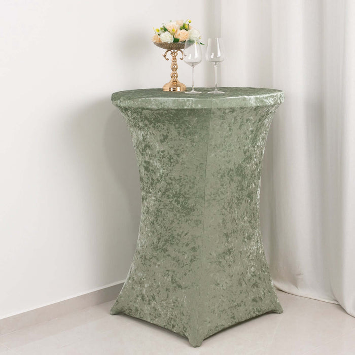 Green table cover draped over a round table with decorative items on top.